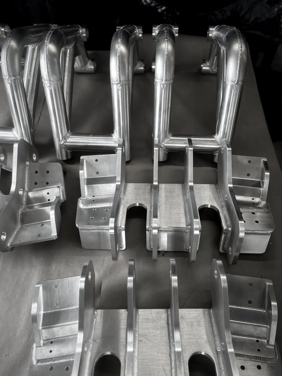 Aluminum TIG welded bracket assemblies and bent-tube assemblies laid out in rows
