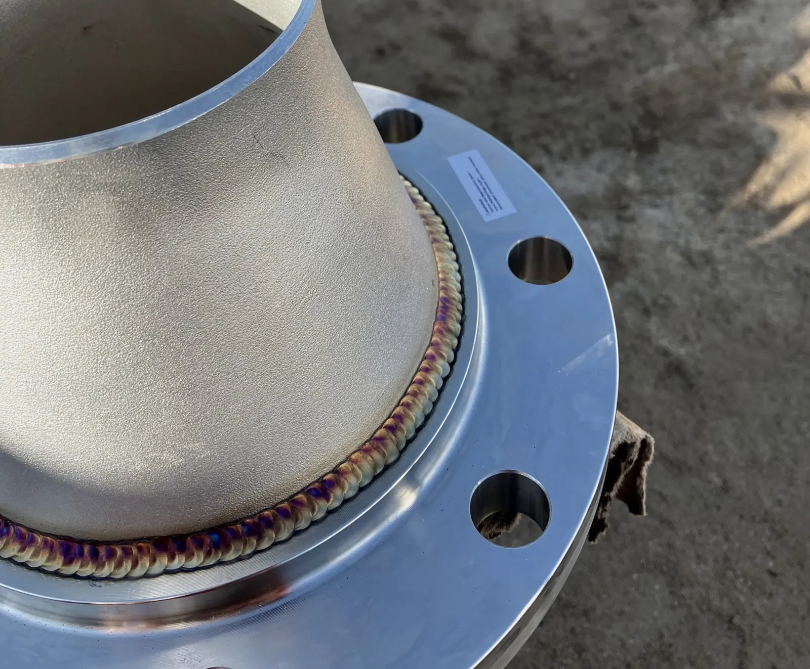 Stainless reducer TIG welded to a flange, with heat tint along the weld